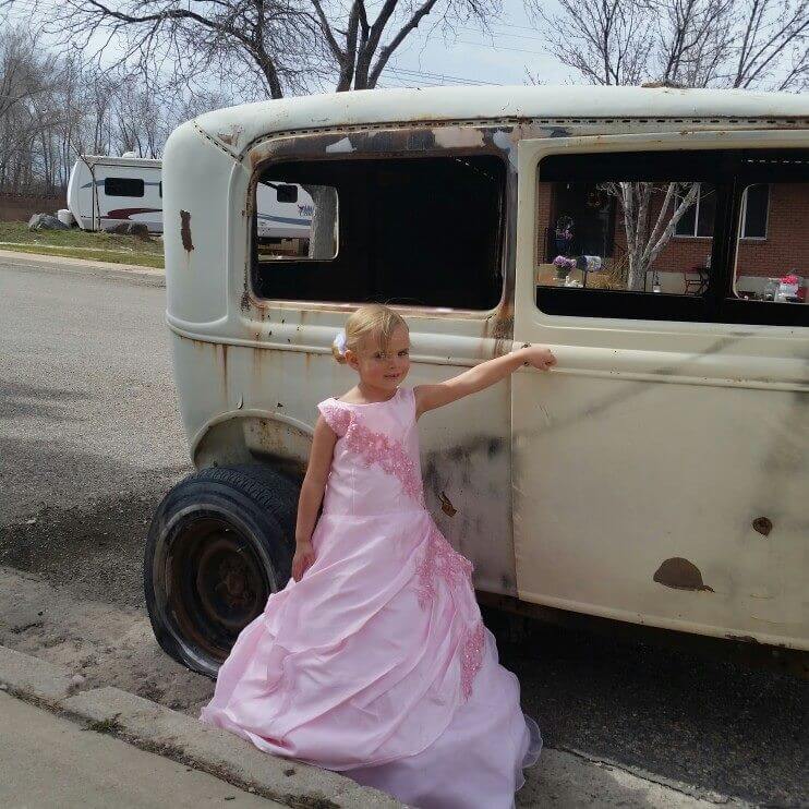 little girl in pink cinderella dress in front of old classic car
